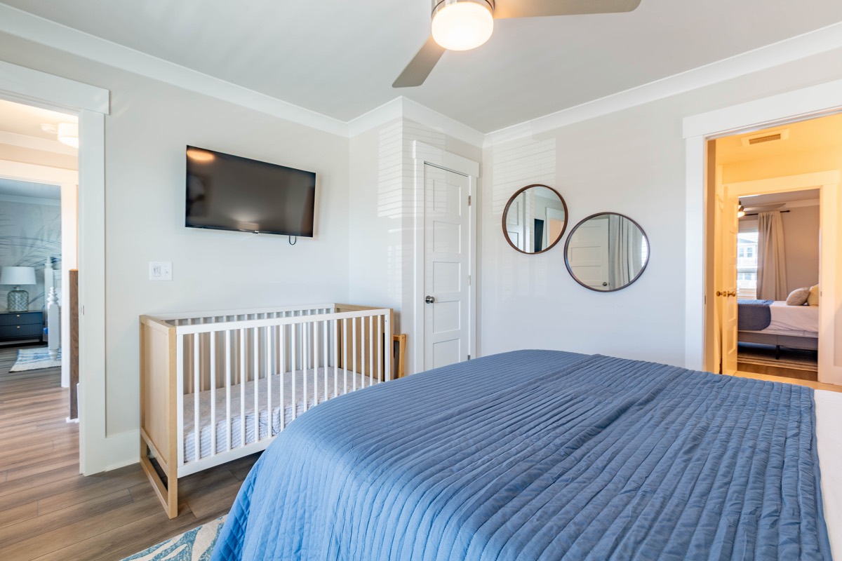 Bedroom with a crib and wall-mounted TV